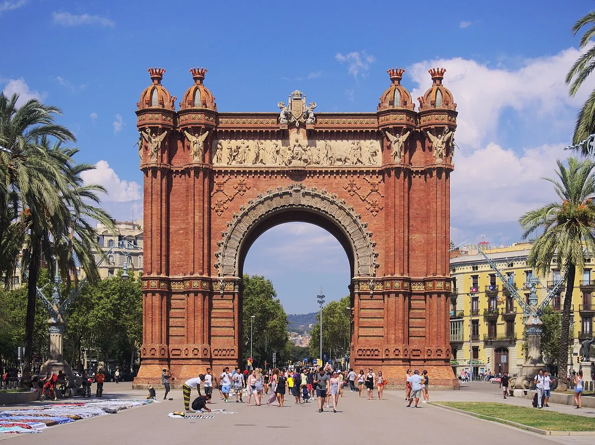 The red-brick Arc de Triomf with its carved stone frieze, seen from the promenade lined with palm trees