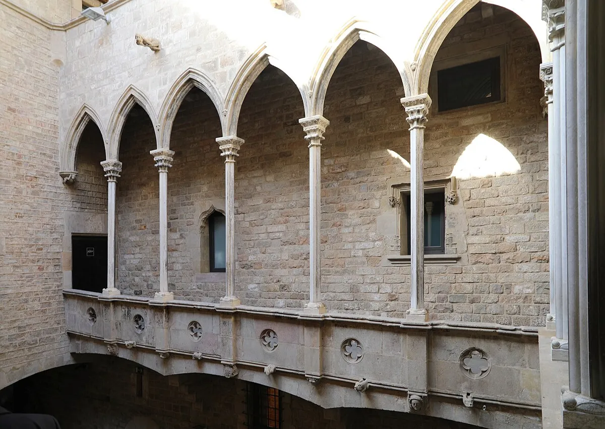 The stone courtyard of Palau Aguilar, with a gallery of slender columns and pointed arches above a stone balustrade