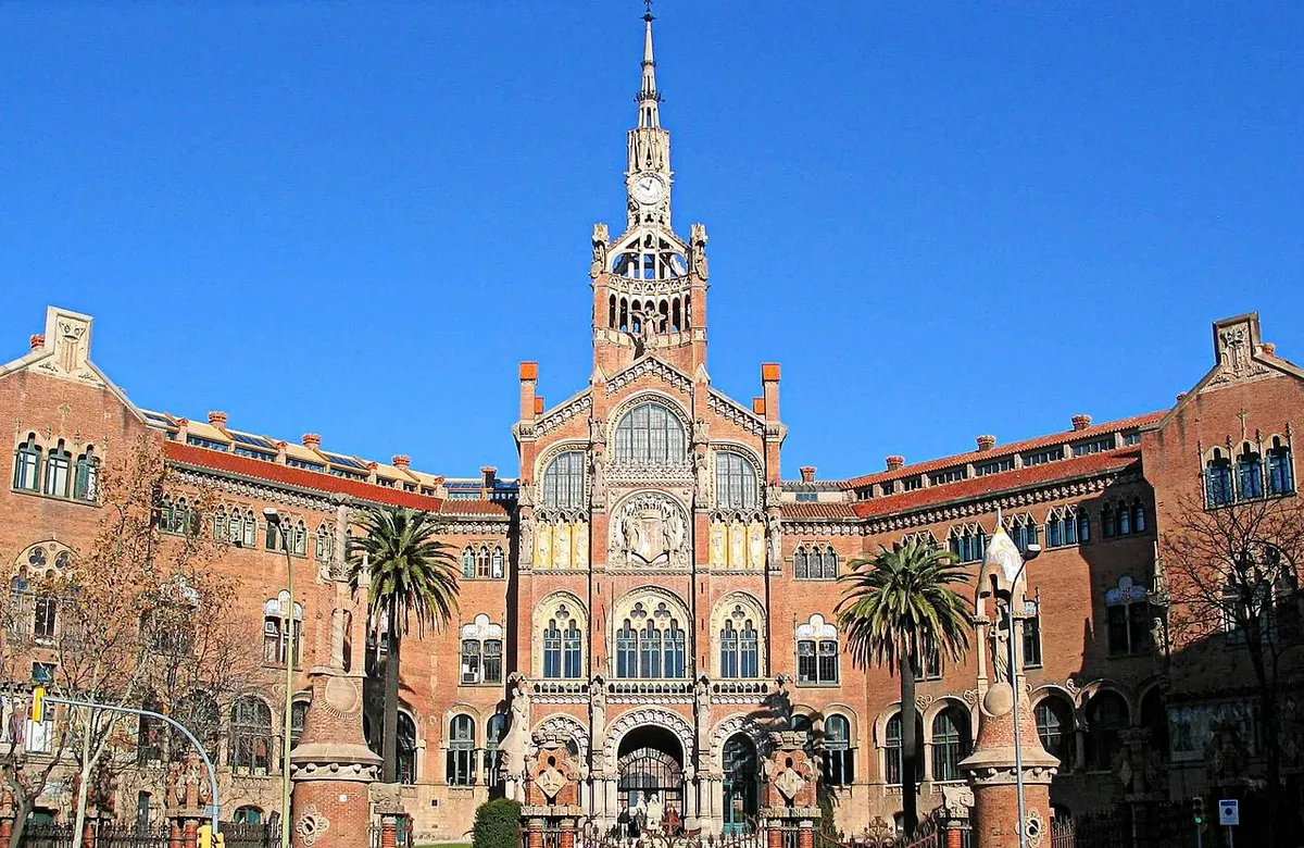 The brick administration pavilion of the Hospital de Sant Pau with its tall clock tower, flanked by palm trees