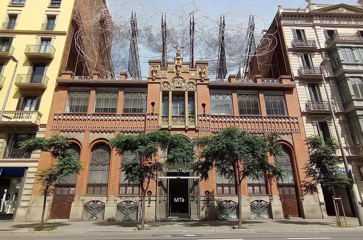 The red-brick and iron façade of the Museu Tàpies on Carrer d'Aragó, topped by a large tangle of metal wire