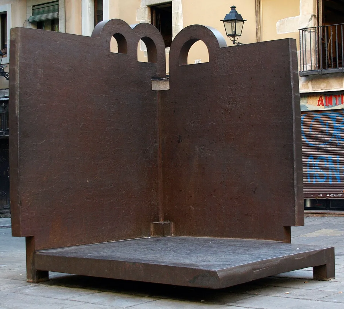 Topos V, a rust-brown iron sculpture of two walls meeting at an angle, with round openings along the top
