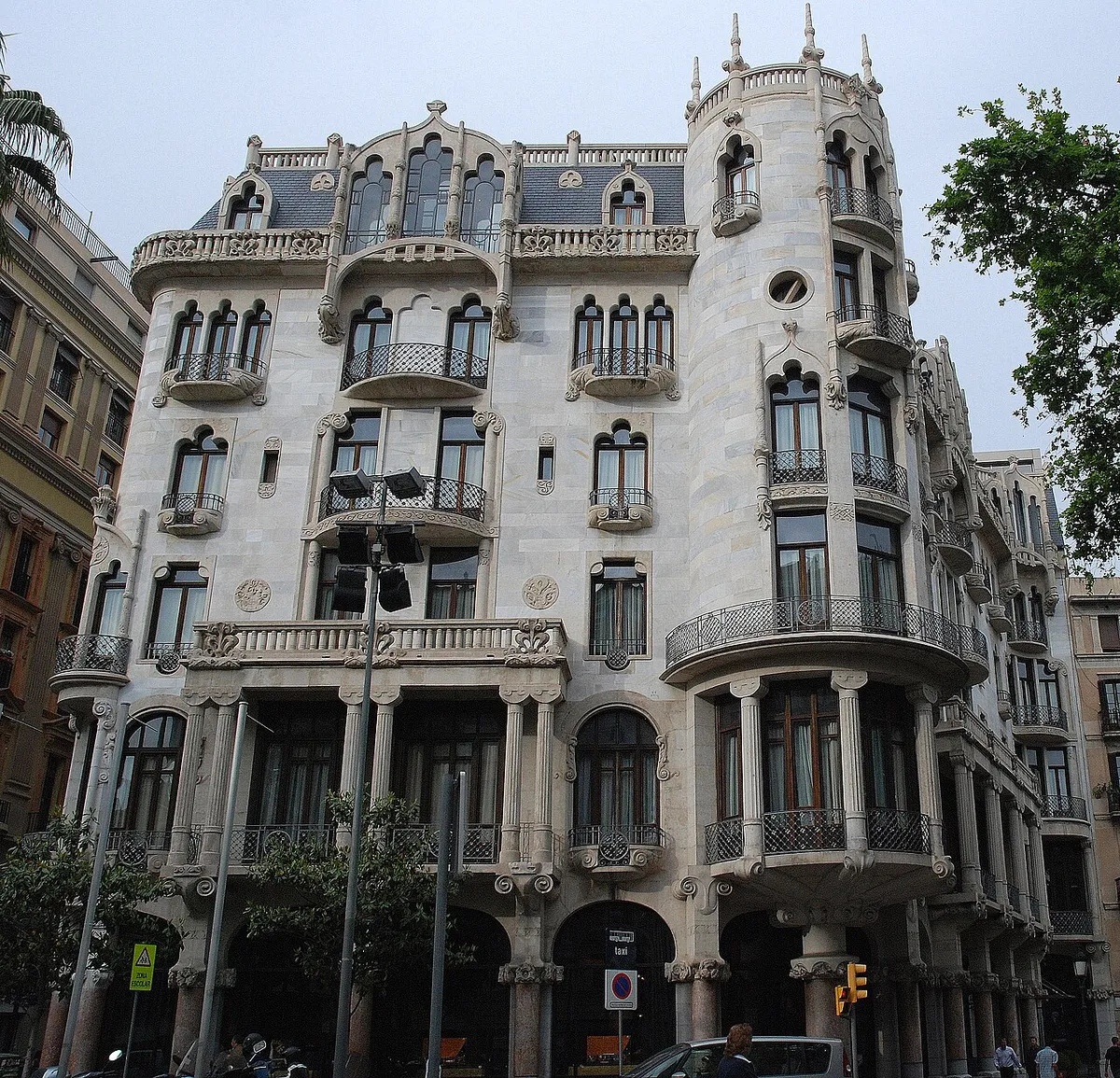 The white stone front of Casa Fuster with its rounded corner tower and red marble columns at street level