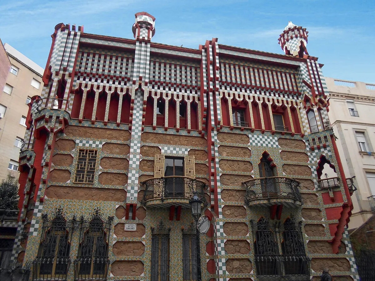 The front of Casa Vicens on Carrer de les Carolines, with bands of green and white tiles, red trim and iron balconies