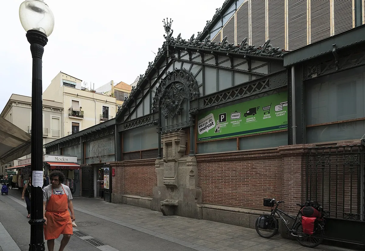 One gable end of the Mercat de la Llibertat, with wrought-iron decoration above bare brick walls on a stone base