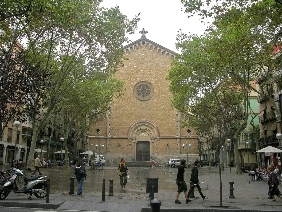 The stone front of the church of Sant Joan at the end of Plaça de la Virreina, framed by plane trees