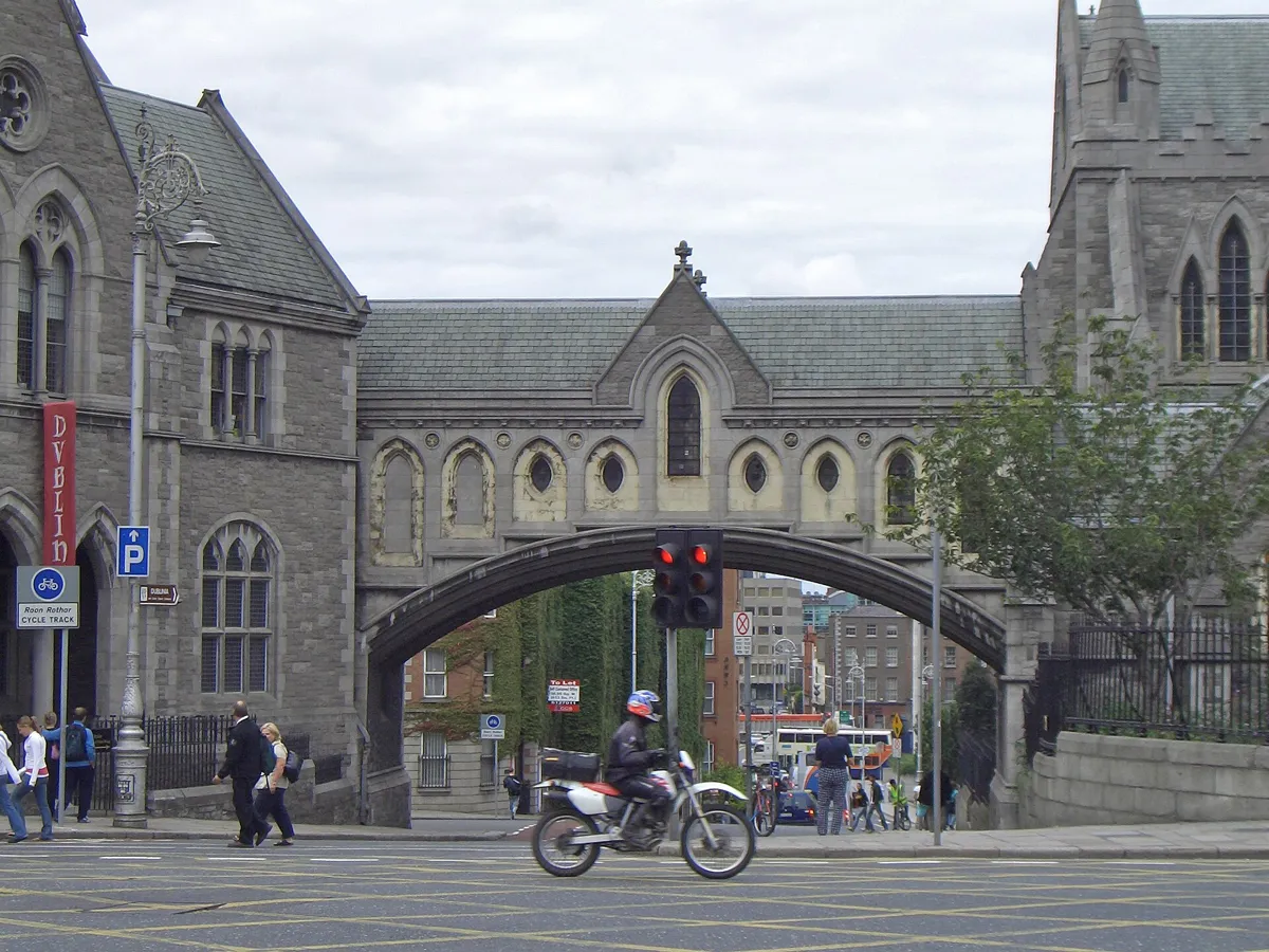 A covered stone bridge with Gothic windows arching over Winetavern Street, joining Christ Church Cathedral on the right to the Synod Hall on the left