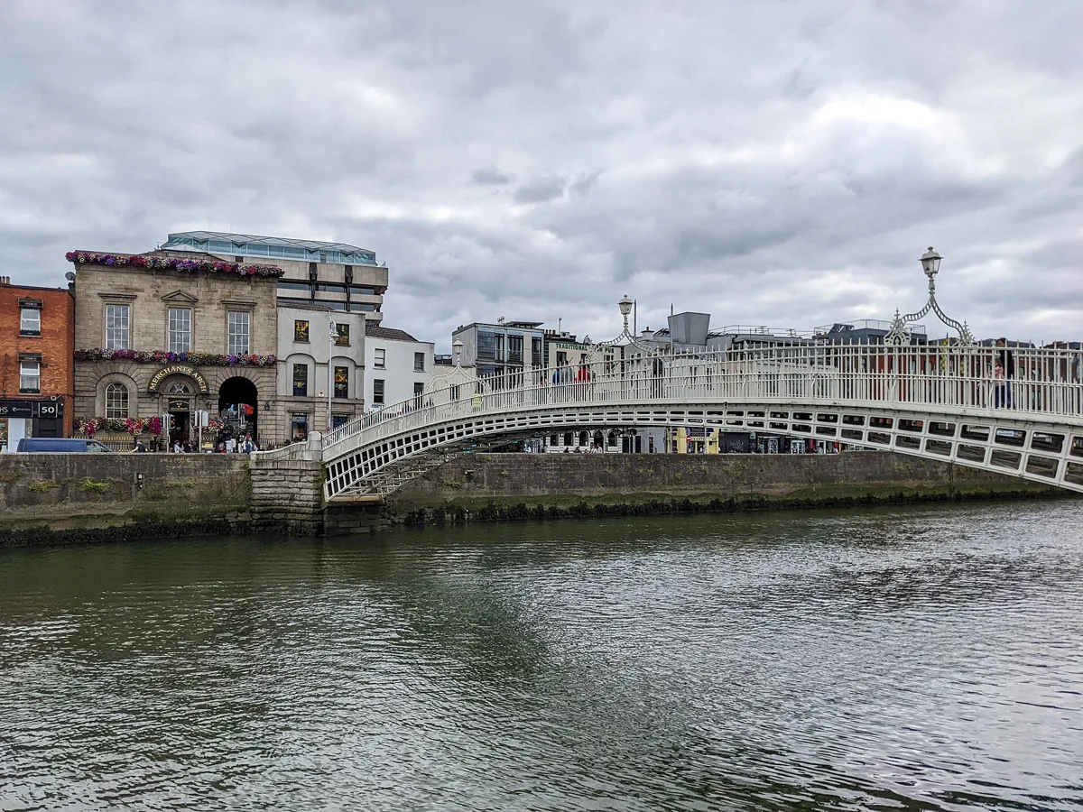 The white cast-iron arch of the Ha'penny Bridge over the River Liffey, with Merchant's Arch and its flower boxes on the far bank