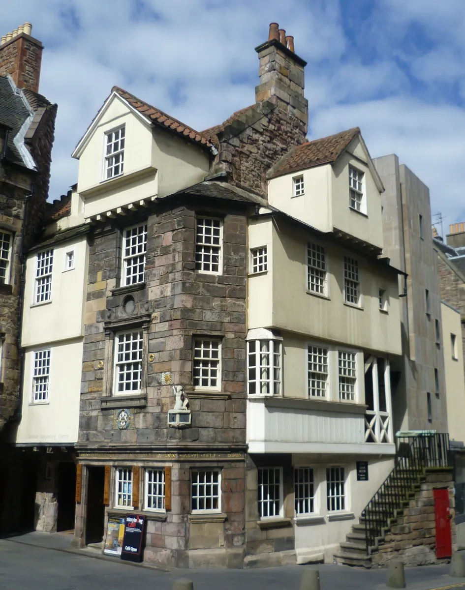 John Knox House, an old house of dark stone and cream render with timber upper storeys, small-paned windows, a carved figure and sundial on the corner and an outside stair
