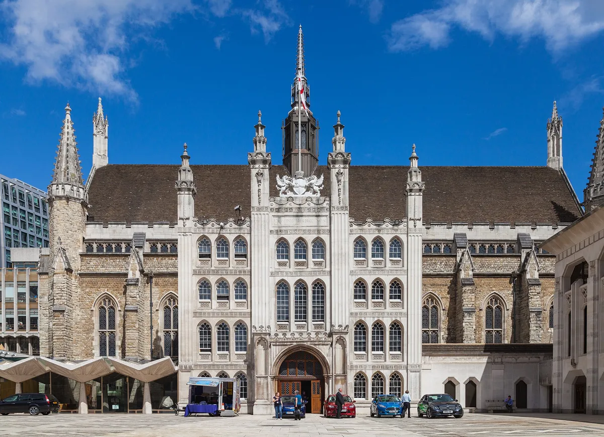 The Gothic stone front of Guildhall across the paved Guildhall Yard, with pinnacles, a tall central porch and a flag on the roof