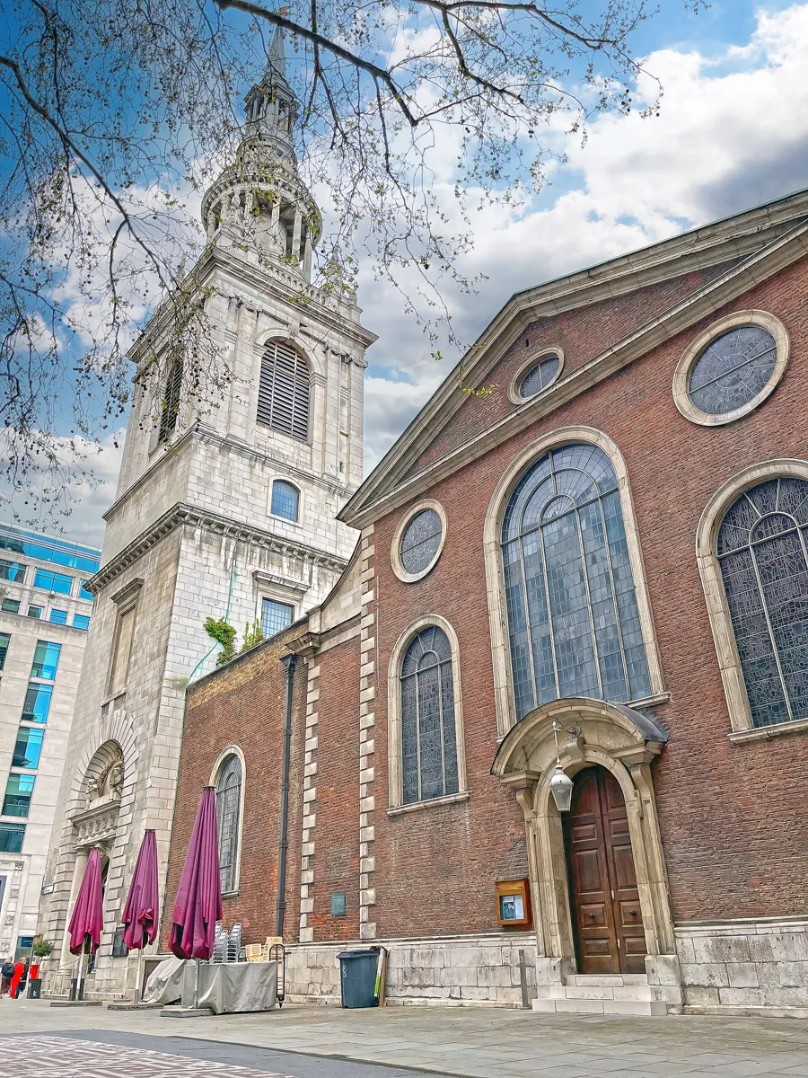 St Mary-le-Bow on Cheapside: a red-brick church with tall arched windows and a stone doorway, beside a white stone tower topped by a spire ringed with columns