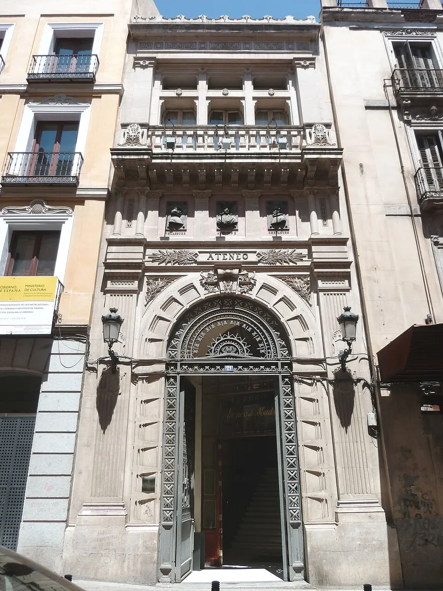 The narrow carved stone front of the Ateneo de Madrid, with a tall arched doorway, the word ATENEO above it and an ornate balcony on top