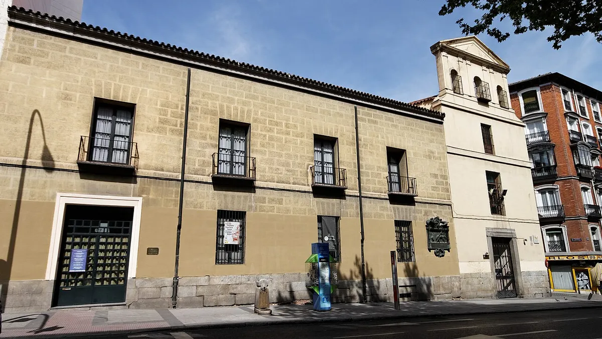 A long, low building with a stone base, rendered walls and barred windows at Calle de Atocha 87, home of the Sociedad Cervantina