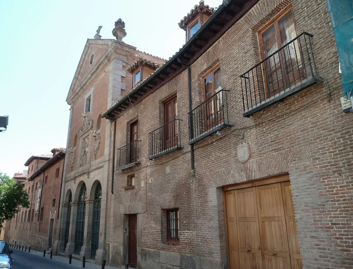 The brick front of the Trinitarias Descalzas convent on Calle de Lope de Vega, with a stone church front and three round arches on the left and windows and balconies along the convent wall