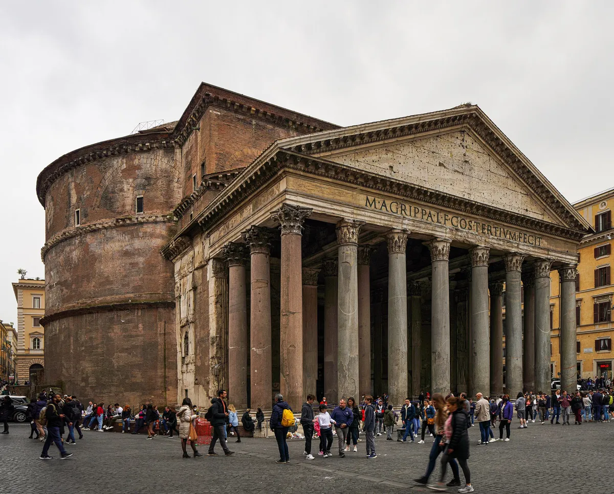 The Pantheon from Piazza della Rotonda: a brick drum on the left and a deep porch of granite columns under a pediment carved with M AGRIPPA, with crowds in front
