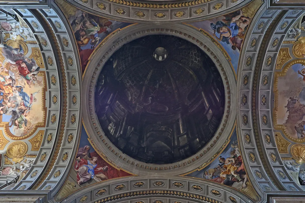 Looking straight up at a painted circle in the church ceiling that looks like a deep, columned dome with a lantern, surrounded by frescoes and gilded coffers