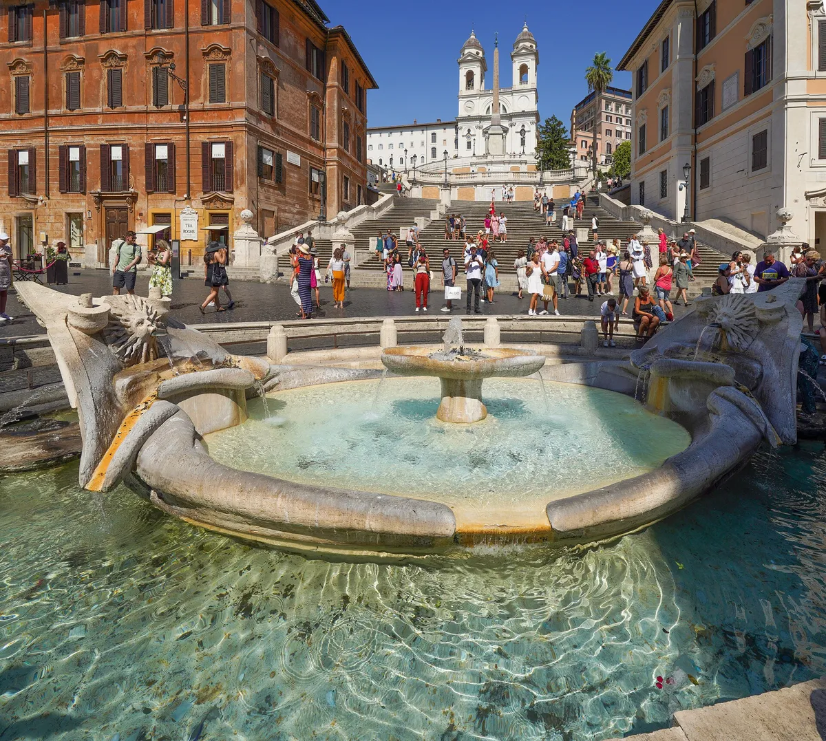 The low, boat-shaped Barcaccia fountain in the foreground, with the Spanish Steps rising behind it to the twin bell towers of Trinità dei Monti and an obelisk